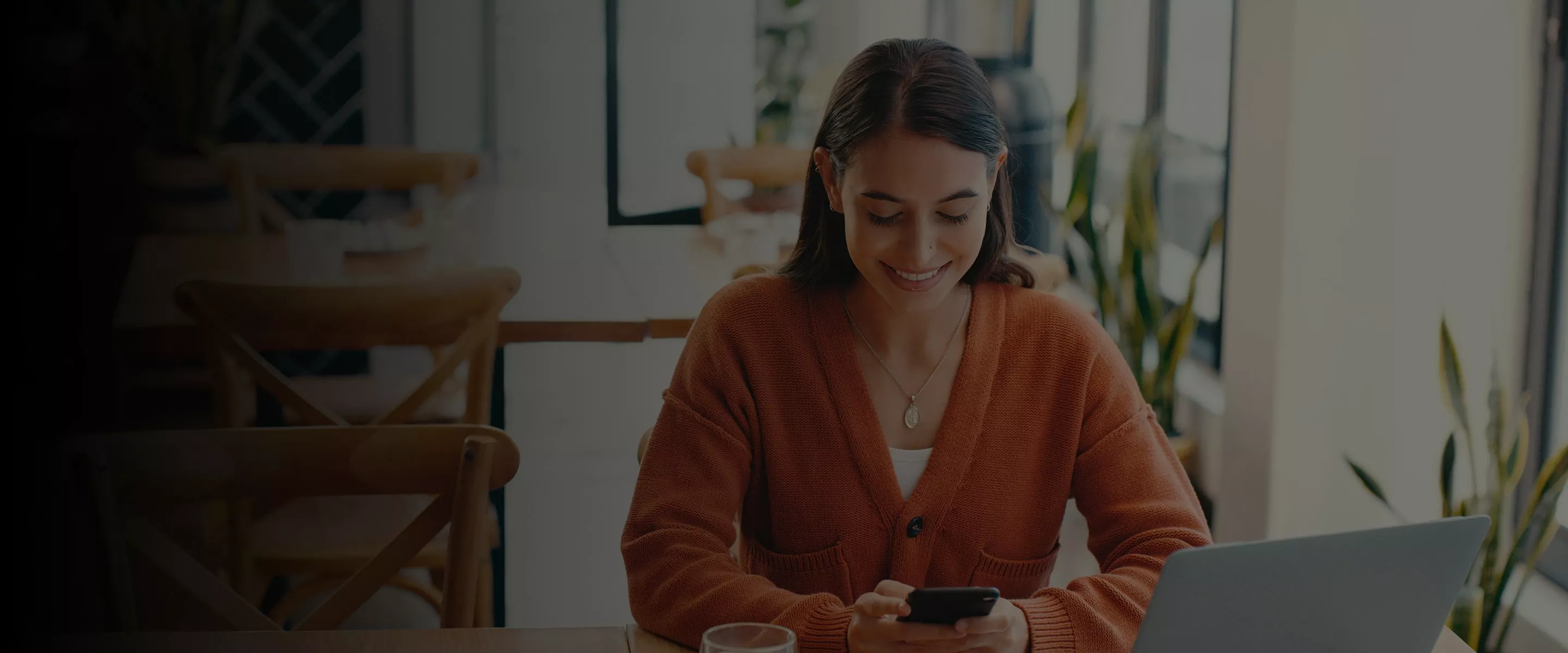 Woman at desk looking at phone banner